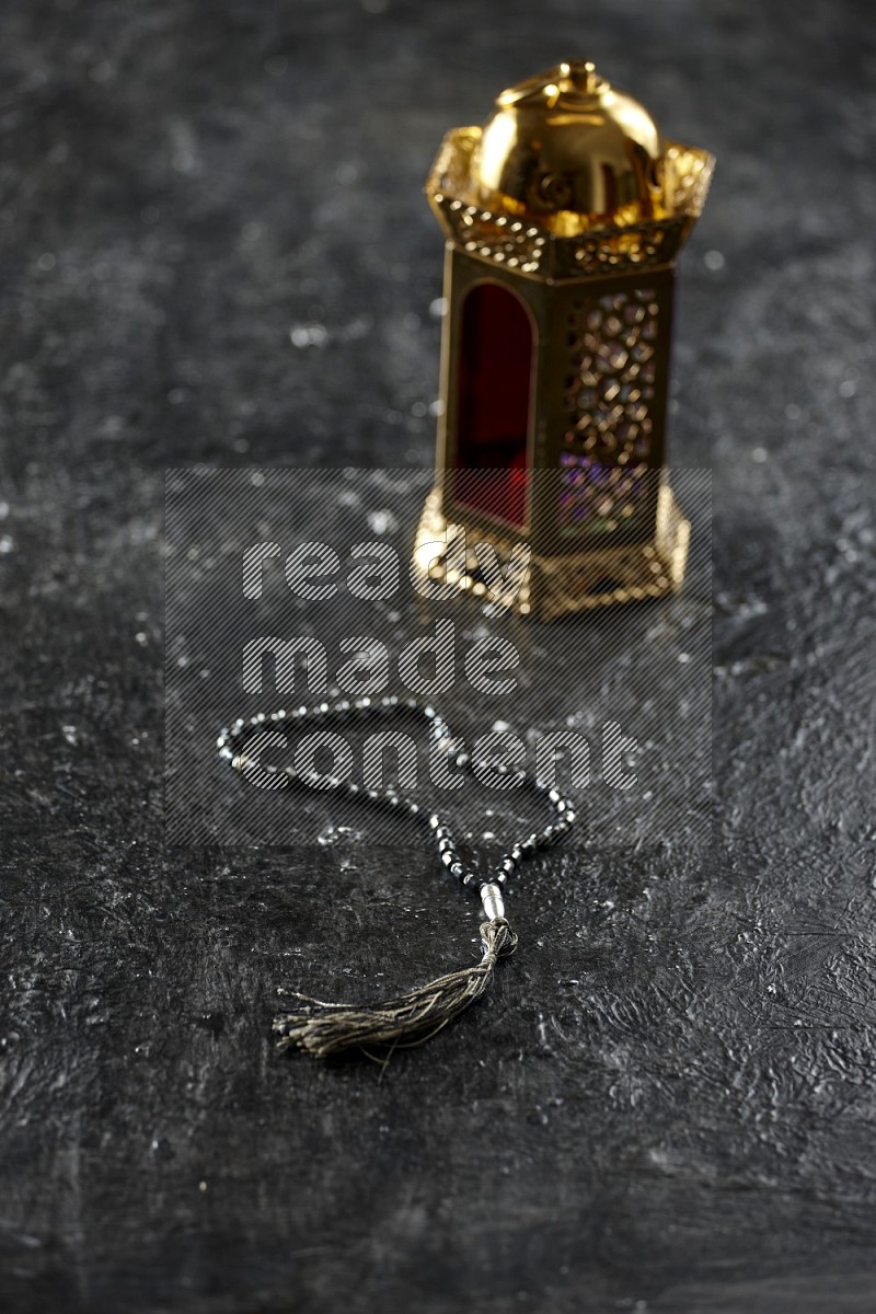 Quran with a prayer beads on textured black background