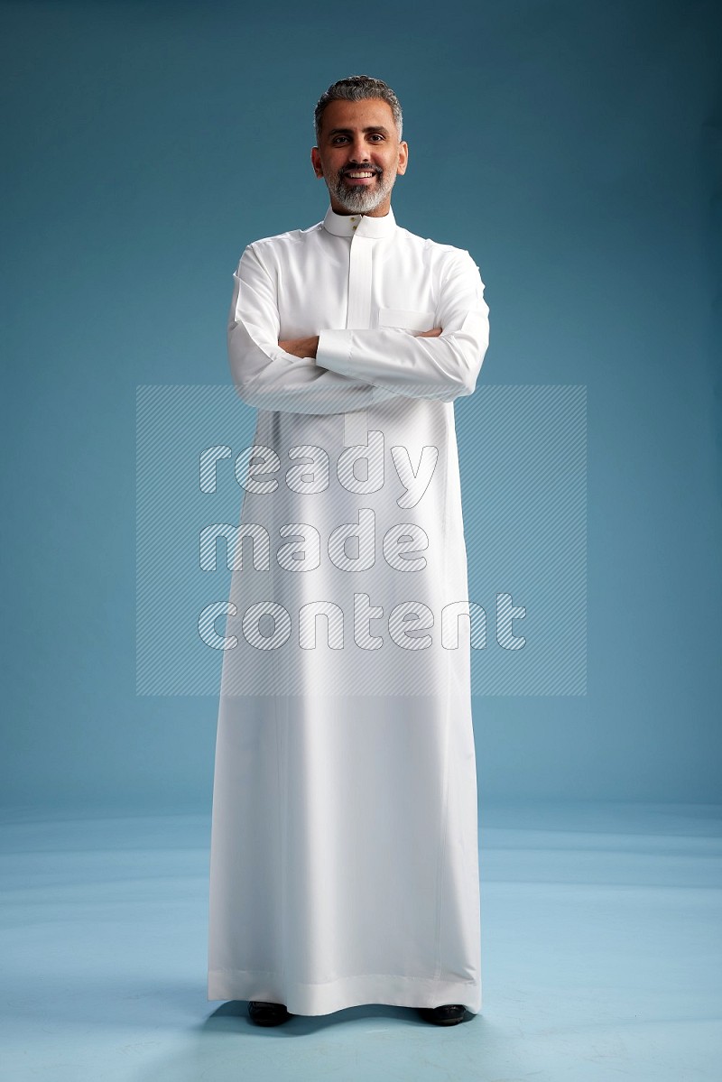 Saudi man waring thob posing to the camera on blue background