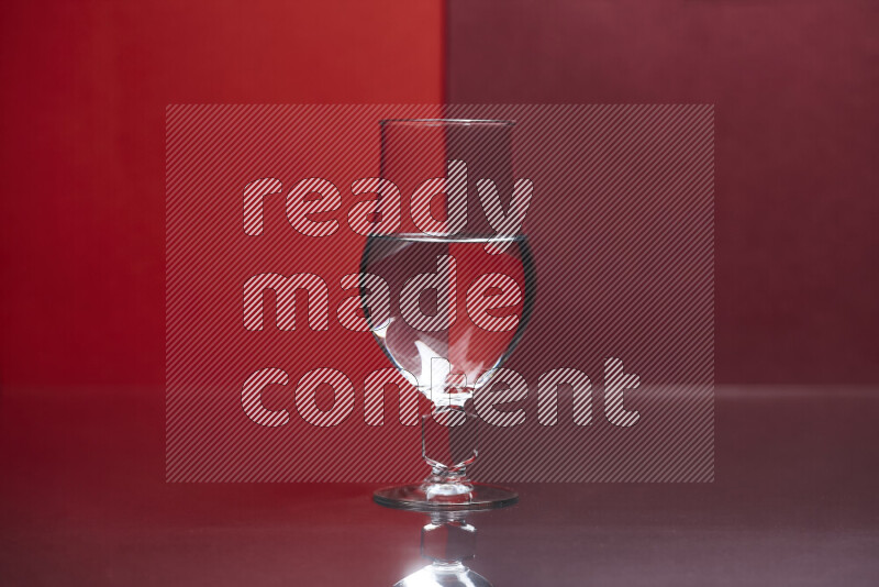 The image features a clear glassware filled with water, set against red and dark red background