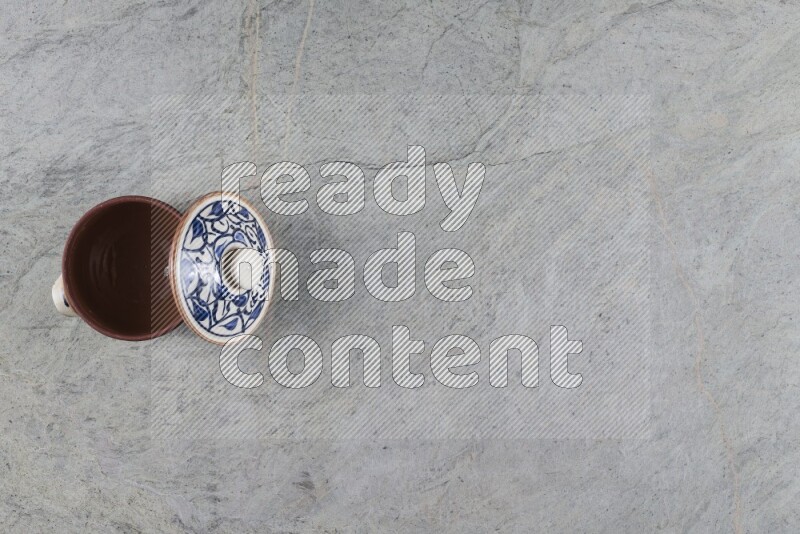 إناء فخاري متعدد الألوان مع غطائه على خلفية من الرخام الرمادي