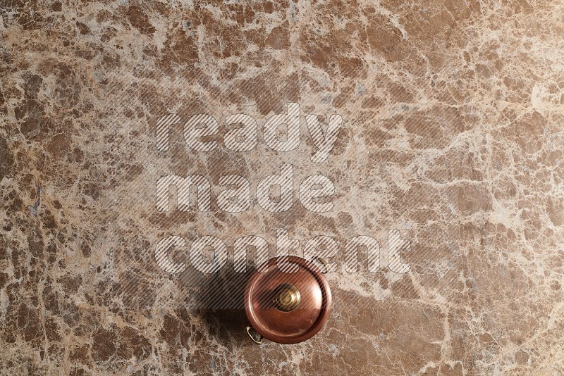 Top View Shot Of A Small Copper Pot On beige Marble Flooring