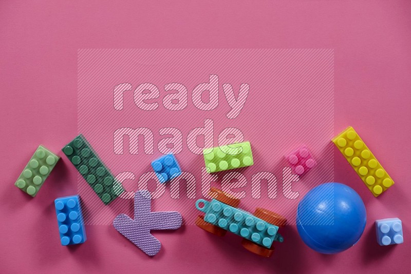 Plastic building blocks with balls on pink background in top view (kids toys)