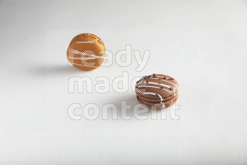 45º Shot of of two assorted Brown Irish Cream, and Brown white Chocolate Caramel macarons on white background