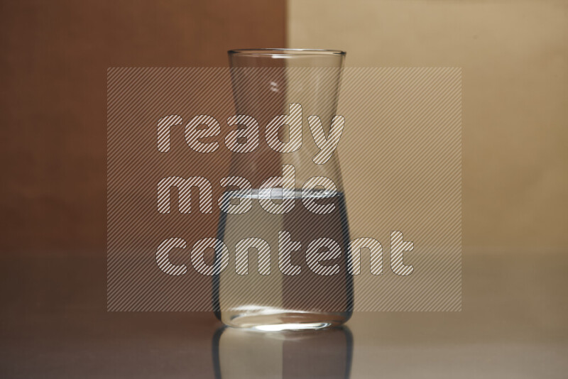 The image features a clear glassware filled with water, set against brown and beige background