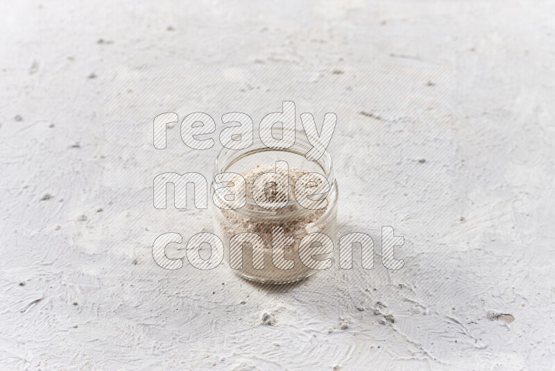 A glass jar full of onion powder on white background