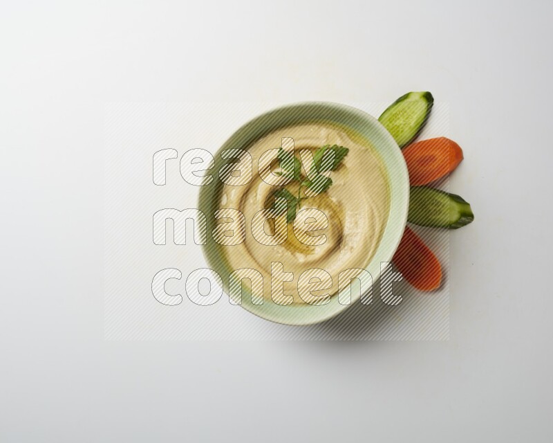 Hummus in a green plate garnished with parsley on a white background