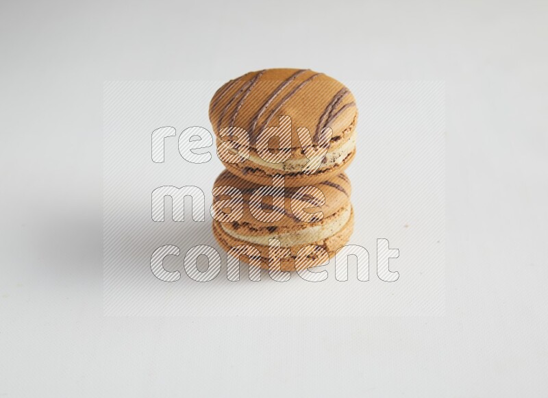 45º Shot of two light brown  Almond Cream macarons on white background