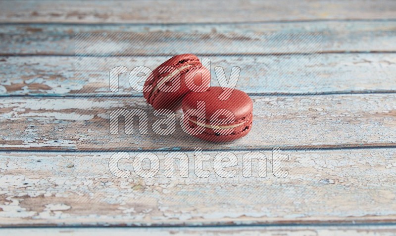 45º Shot of two Red Velvet macarons on light blue wooden background
