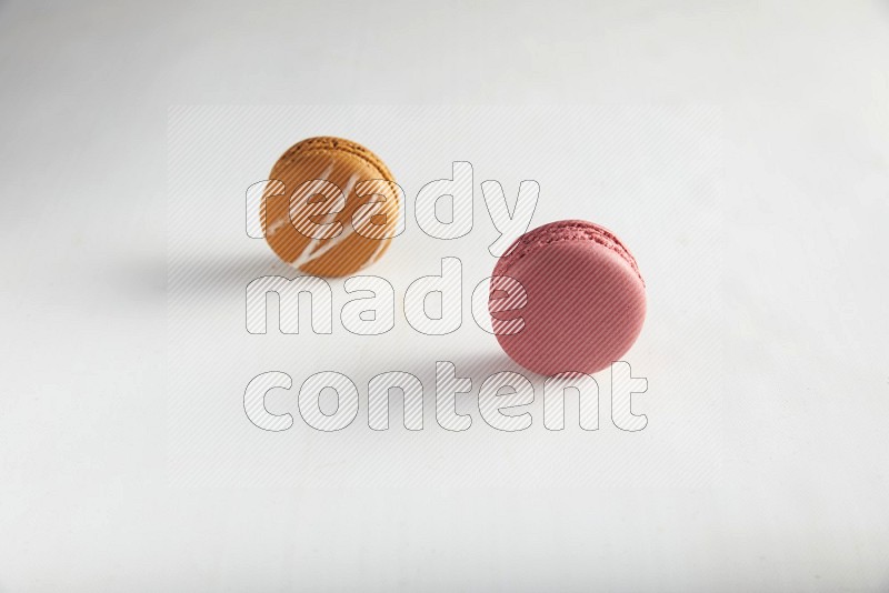 45º Shot of of two assorted Brown Irish Cream, and Pink Raspberry macarons on white background