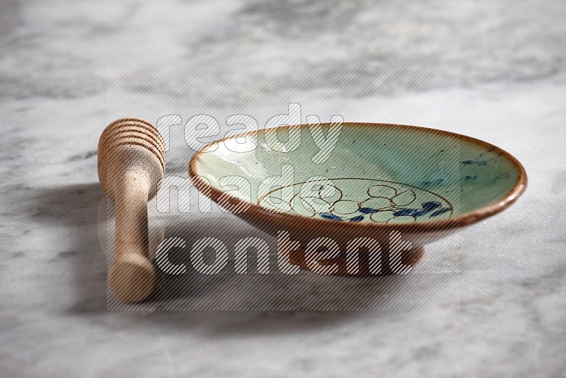 Decorative Pottery Plate with wooden honey handle on the side with grey marble flooring, 15 degree angle