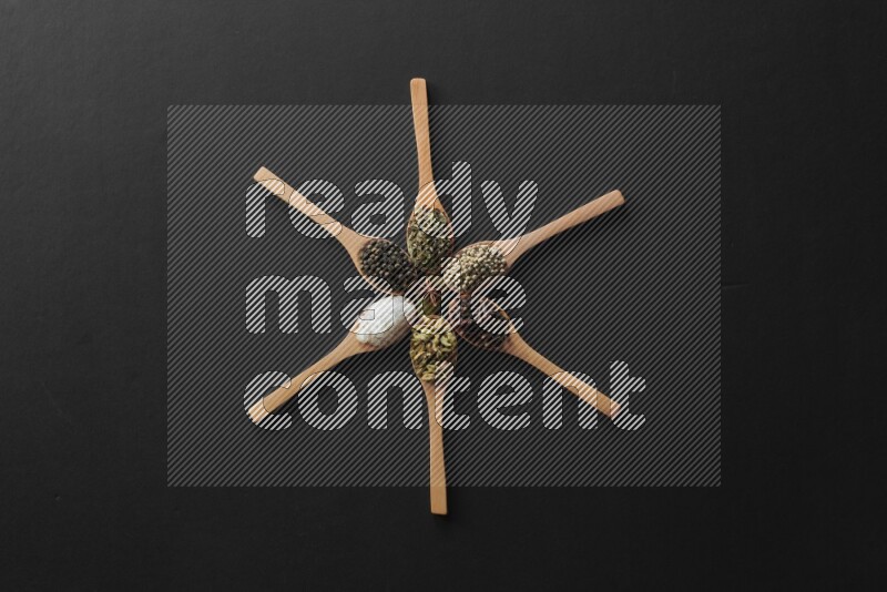 الفلفل الأبيض والقرنفل والهيل والملح والفلفل الأسود والريحان المجفف في معالق خشبية علي شكل ساعة علي خلفية سوداء