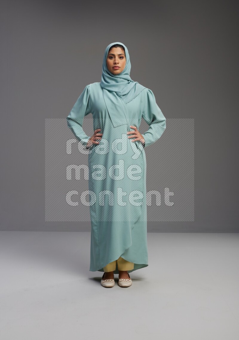 Saudi Woman wearing Abaya standing interacting with the camera on Gray background
