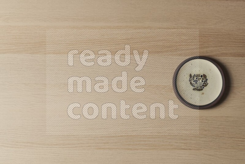 صحن فخاري مزخرف على خلفية خشبية فاتحة