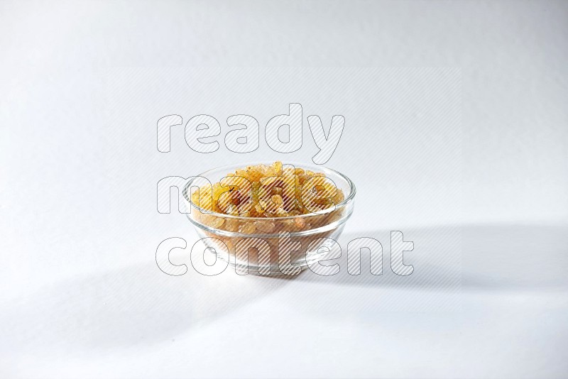 A glass bowl full of raisins on a white background in different angles