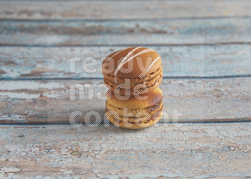 45º Shot of of two assorted Brown Irish Cream, and Yellow Crème Brulée macarons on light blue background