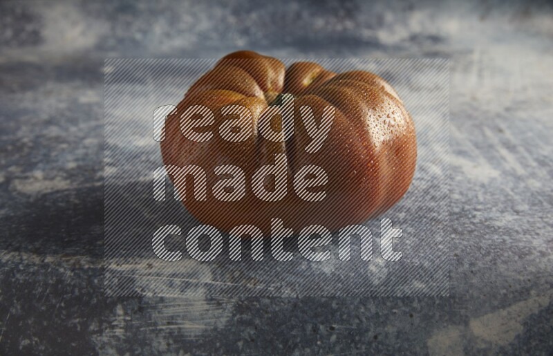 45 degree single heirloom tomato on a textured rustic blue background