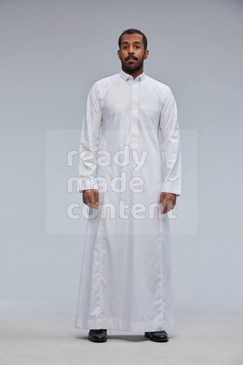 Saudi man Wearing Thob standing interacting with the camera on Gray background