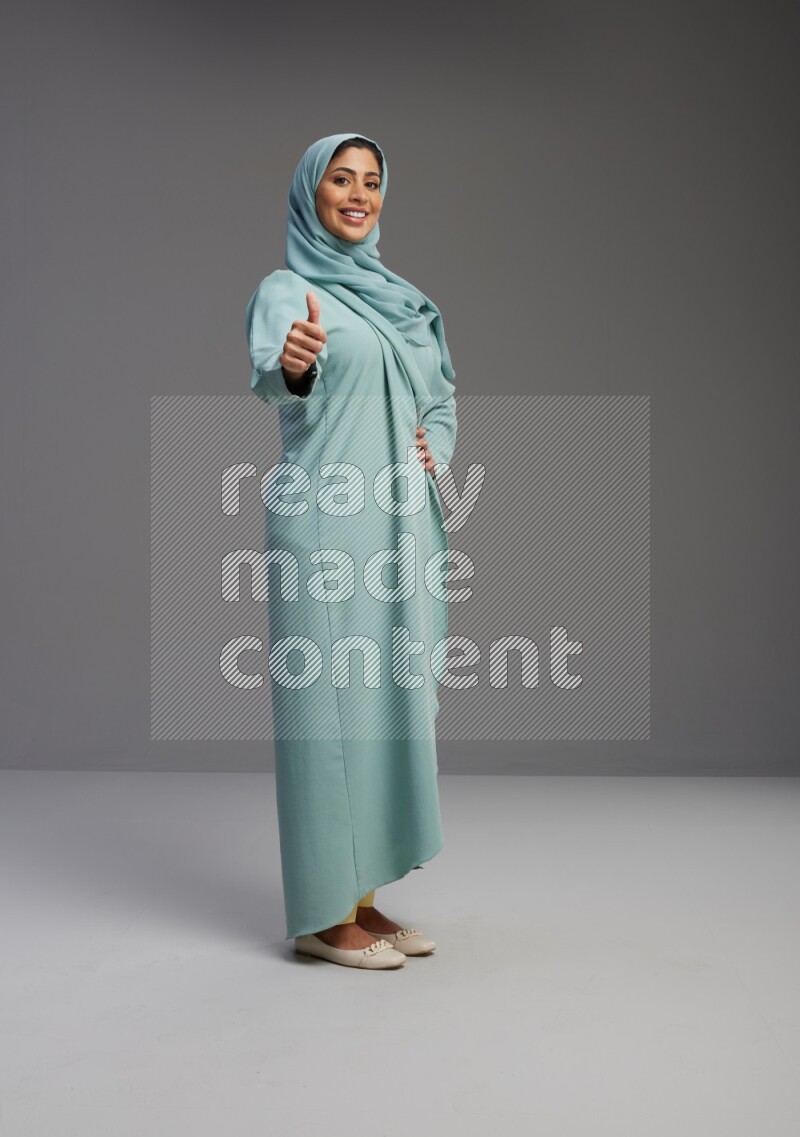 Saudi Woman wearing Abaya standing interacting with the camera on Gray background