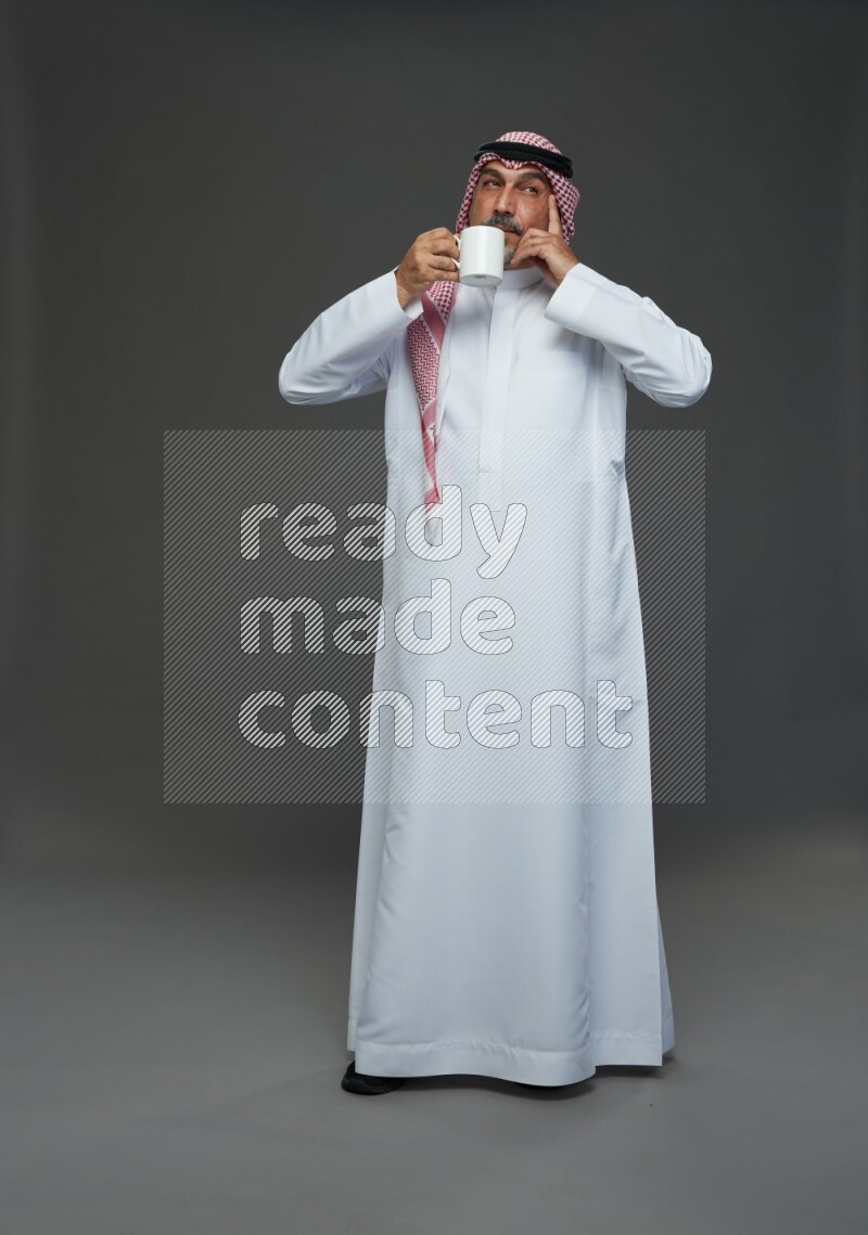Saudi man with shomag Standing holding mug on gray background