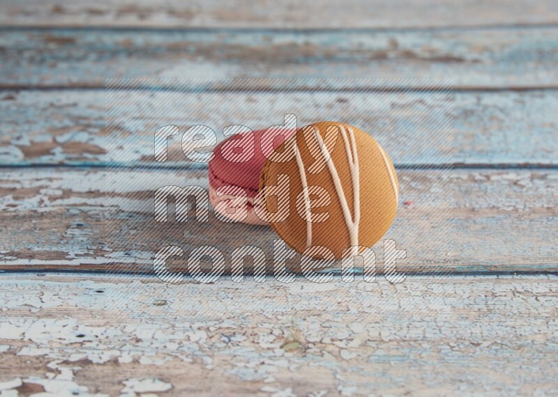45º Shot of of two assorted Brown Irish Cream, and Pink Litchi Raspberry macarons on light blue background