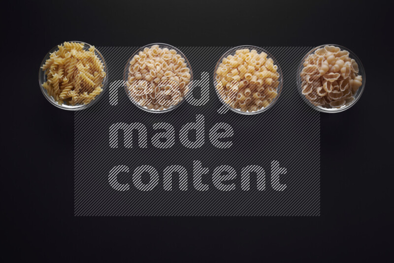 أنواع مختلفة من المعكرونة في وعاء زجاجي علي خلفية سوداء