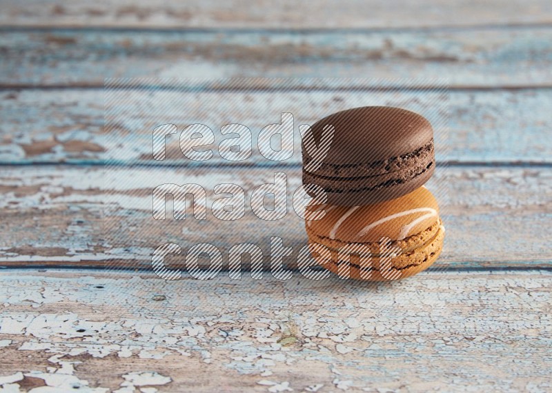 45º Shot of of two assorted Brown Irish Cream, and Brown Dark Chocolate macarons on light blue background