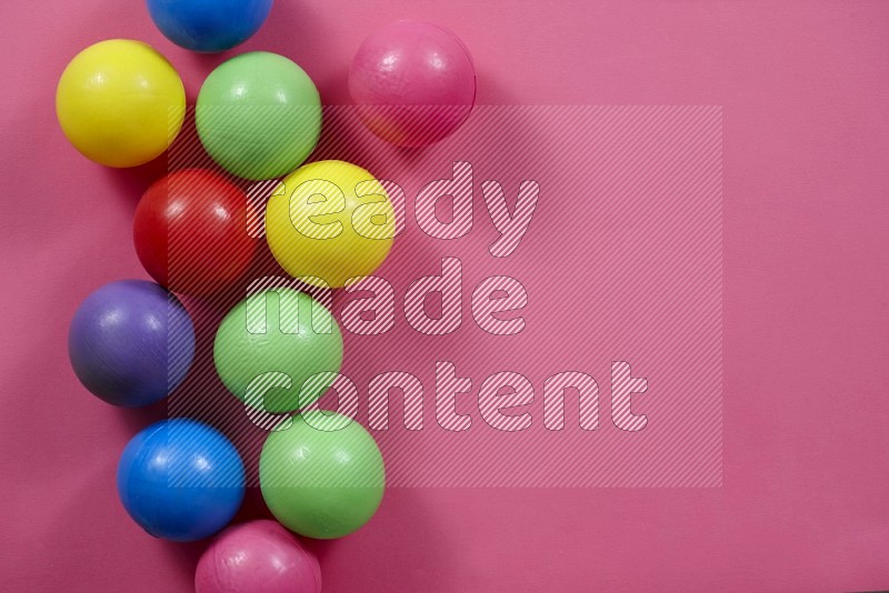 Multicolored plastic balls on yellow background in top view (kids toys)