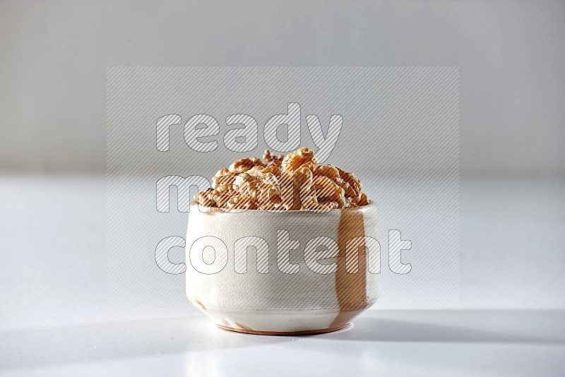 A beige ceramic bowl full of peeled walnuts on a white background in different angles