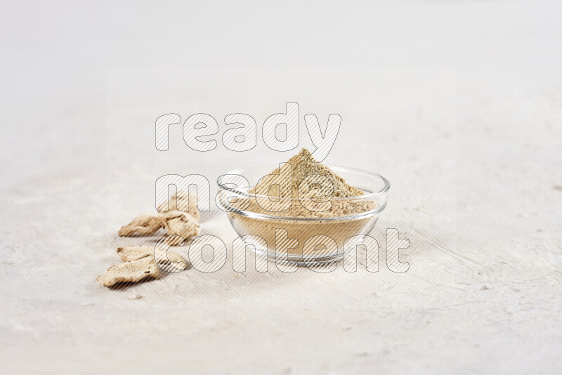 A glass bowl full of ground ginger powder on white background