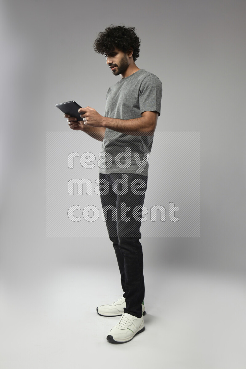 A man wearing casual standing and gaming on a tablet on white background