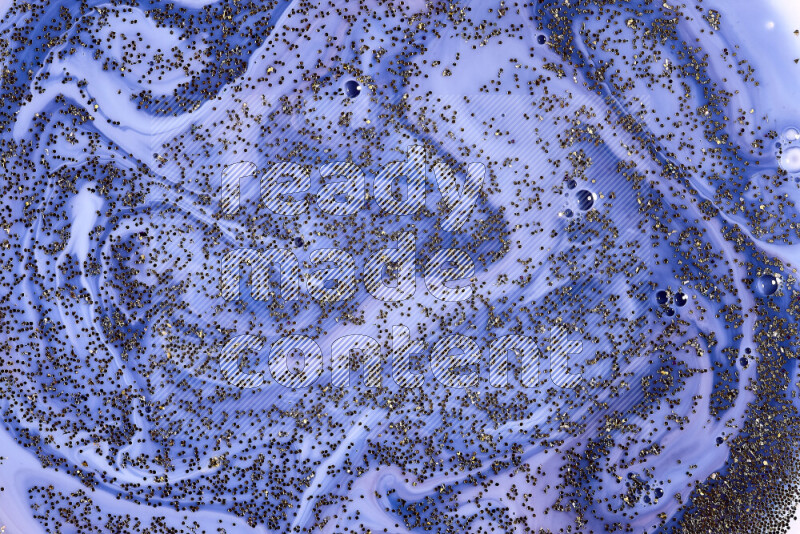 A close-up of sparkling gold glitter scattered on swirling blue background