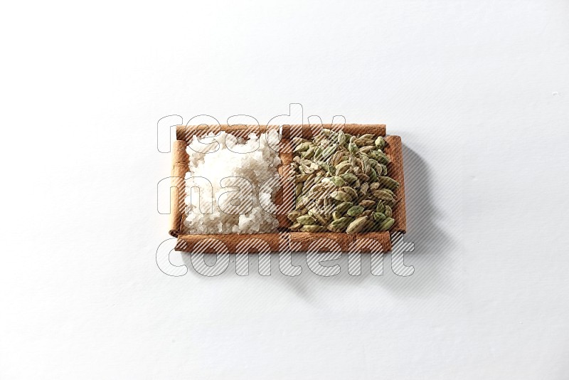 2 squares of cinnamon sticks full of cardamom and white salt on white flooring