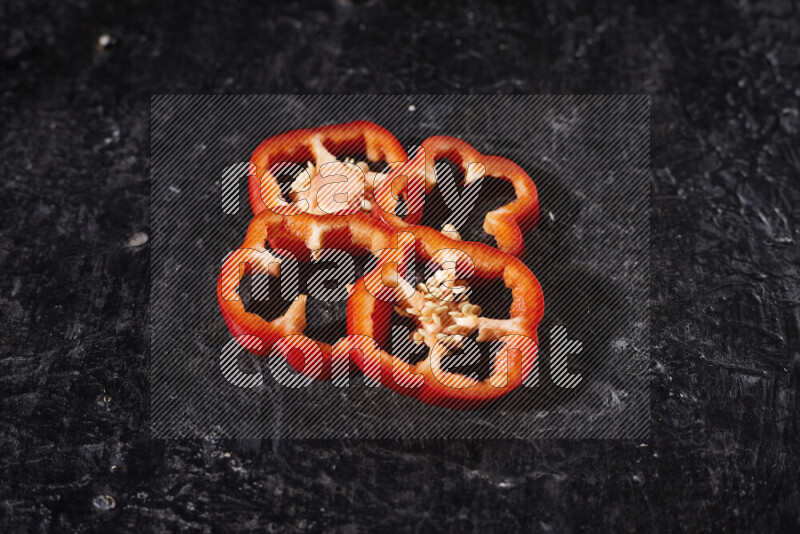 Red bell pepper slices on black background