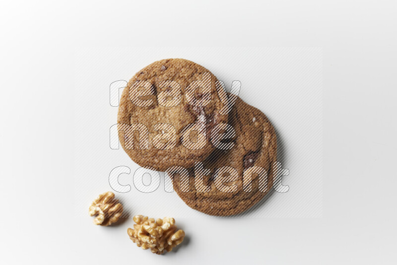 Chocolate chips cookies with walnuts beside it on a white background