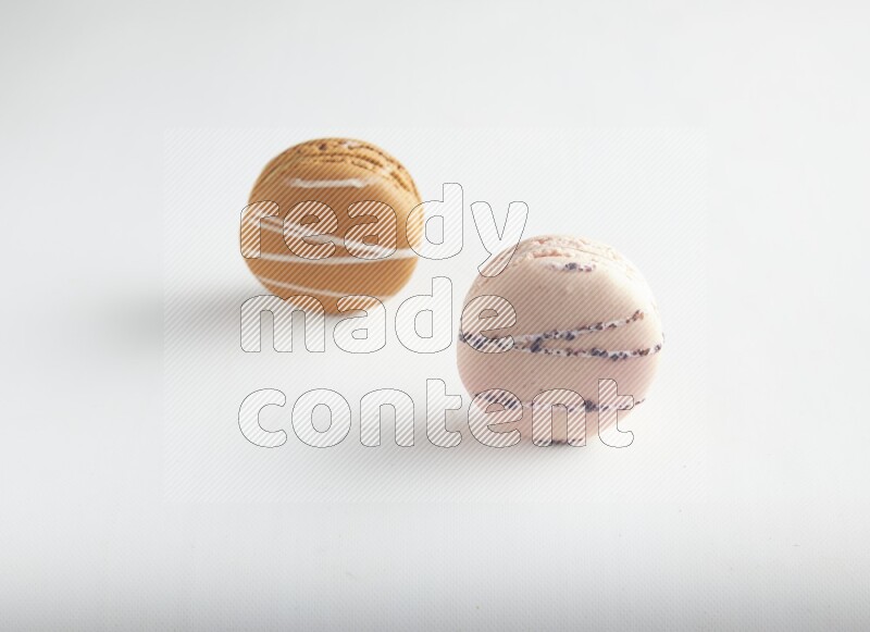 45º Shot of of two assorted Brown Irish Cream, and pink orange blossom macarons on white background