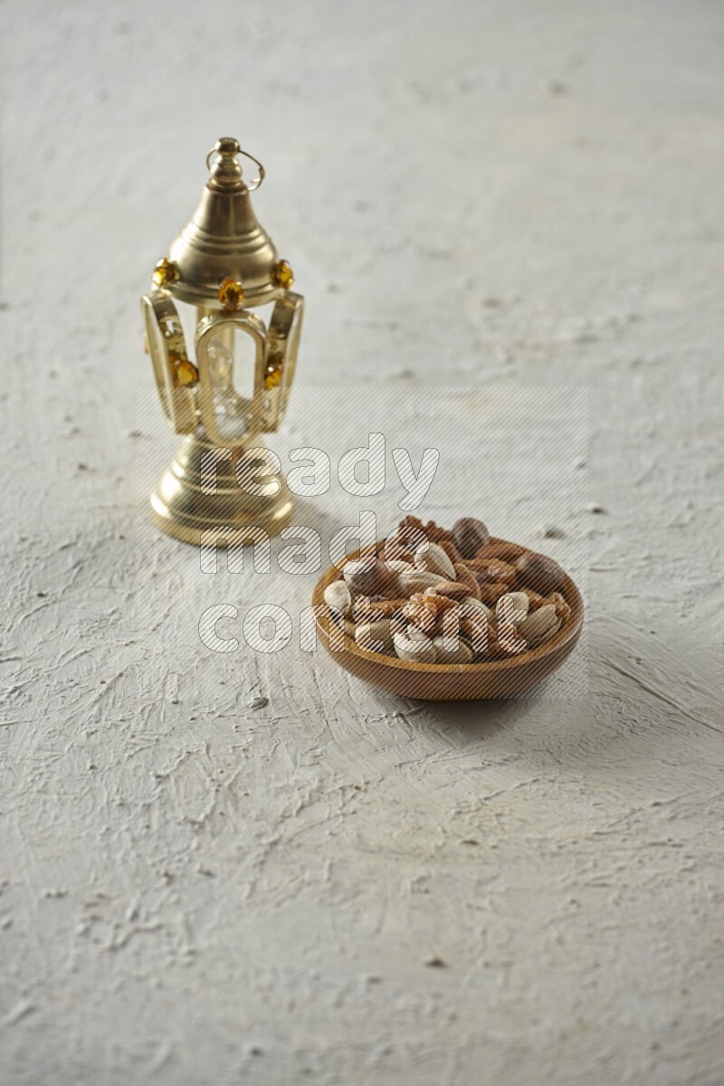 A golden lantern with different drinks, dates, nuts, prayer beads and quran on textured white background