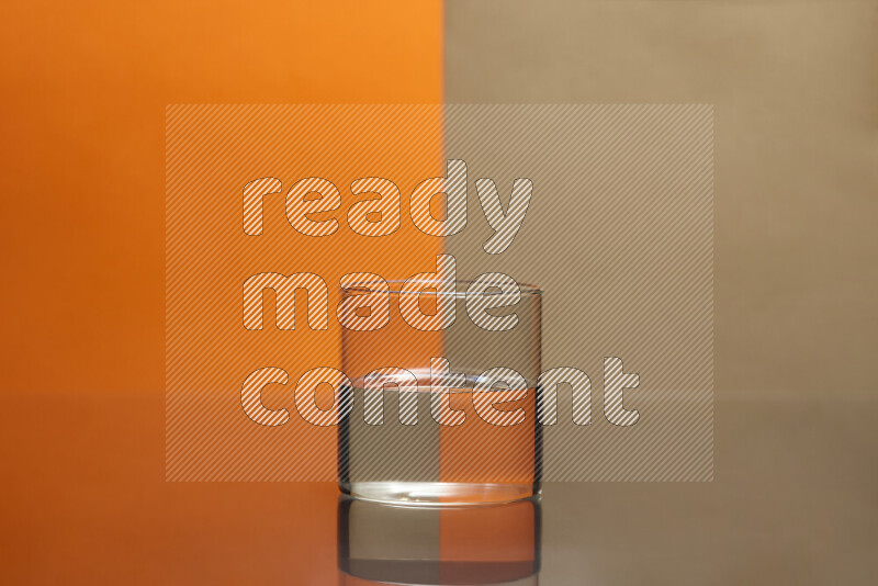 The image features a clear glassware filled with water, set against orange and beige background