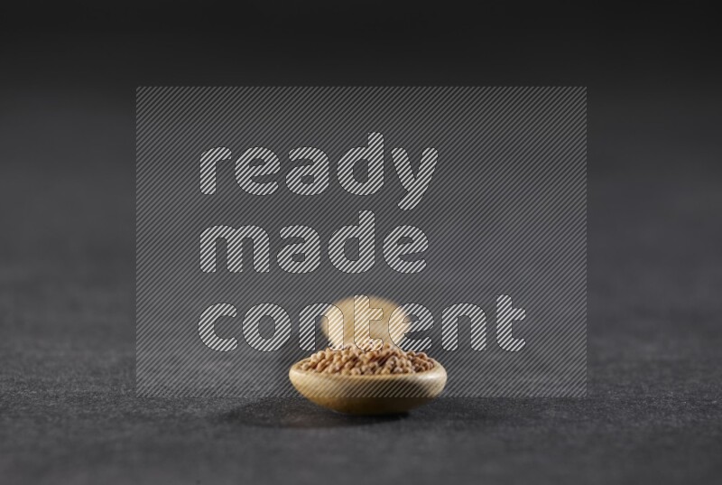 ملعقة خشبية ممتلئة ببذور الخردل علي خلفية سوداء