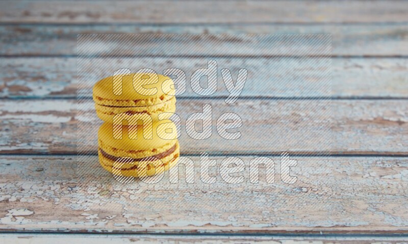 45º Shot of two Yellow Lemon macarons on light blue wooden background