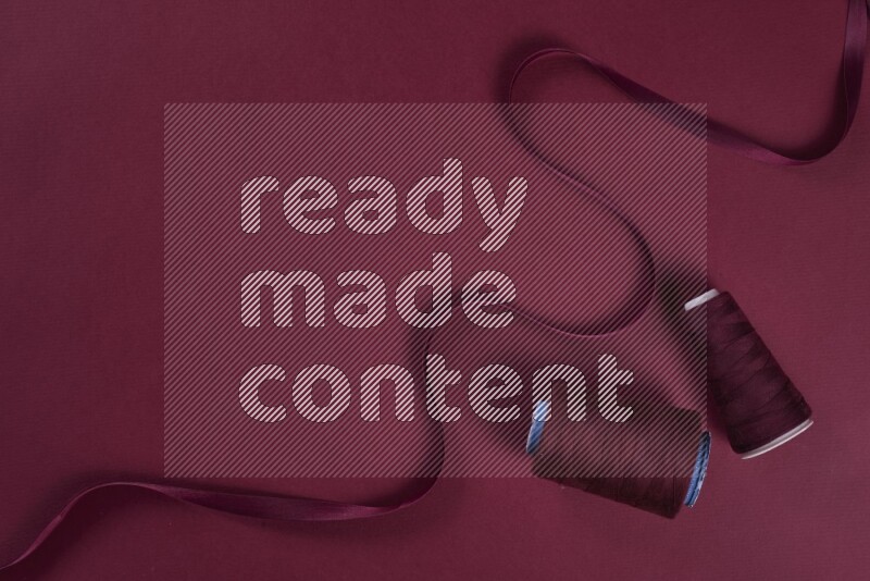 A red collection of sewing and tailoring tools arranged on a red background