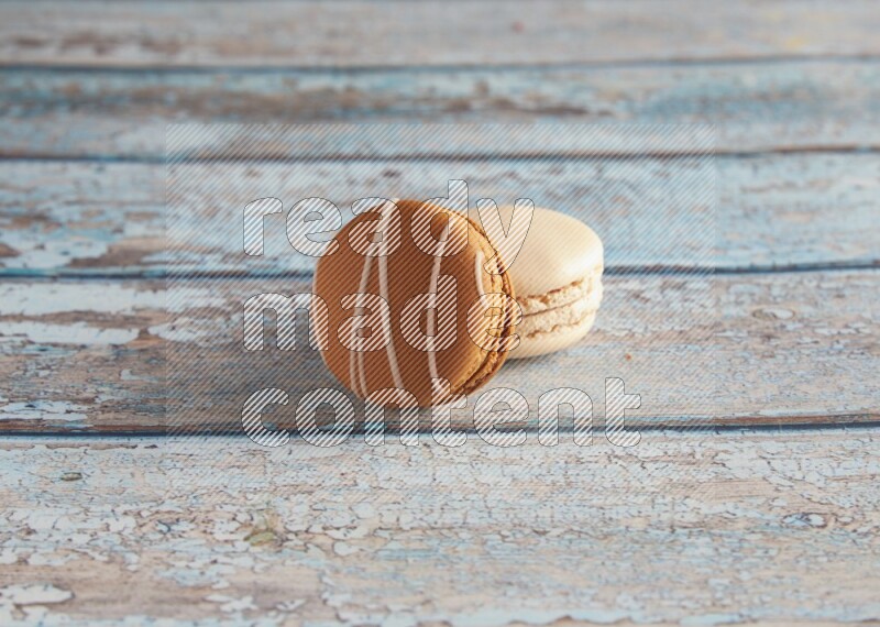 45º Shot of of two assorted Brown Irish Cream, and White Caramel fleur de sel macarons on light blue background