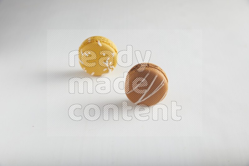 45º Shot of of two assorted Brown Irish Cream, and Yellow Piña Colada macarons on white background