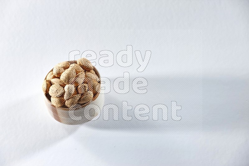 A beige ceramic bowl full of almonds on a white background in different angles