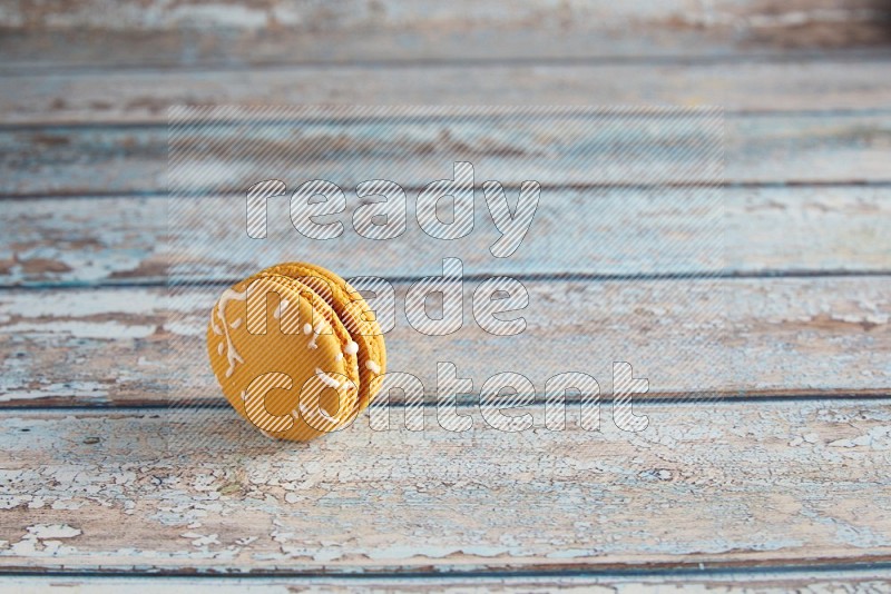 45º Shot of Yellow Piña Colada macaron on light blue wooden background
