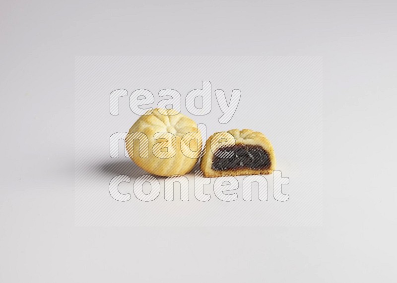 Two Pieces of Maamoul filled with date one of them is cut direct on white background