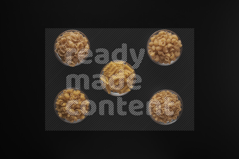 أنواع مختلفة من المعكرونة في أوعية زجاجية علي خلفية سوداء