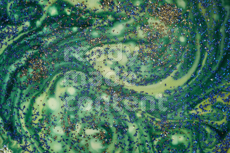 A close-up of sparkling blue glitter scattered on swirling blue and green background