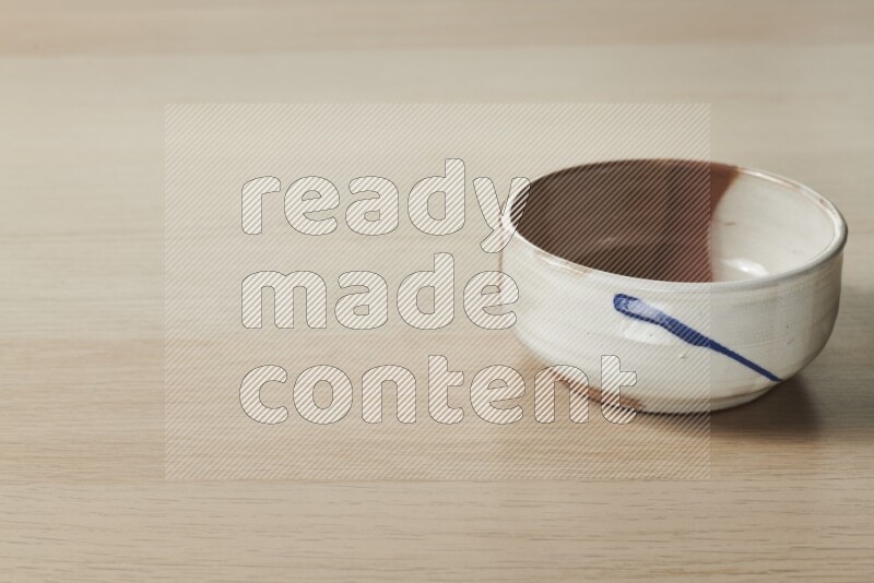 A multicolored pottery bowl on light wooden background