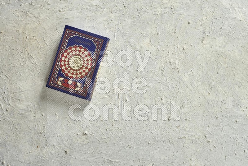 Quran with a prayer beads on textured white background