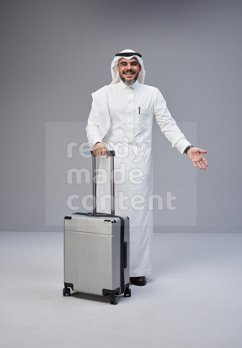 رجل سعودي يرتدي ثوب وشماغ بجانبه حقيبة سفر